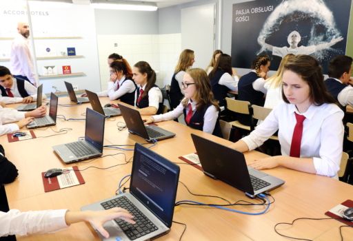 uczniowie w strojach szkolnych w sali komputerowej