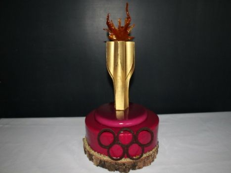 Tort w kształcie znicza olimpijskiego w kolorze złota, brązu i czerwieni