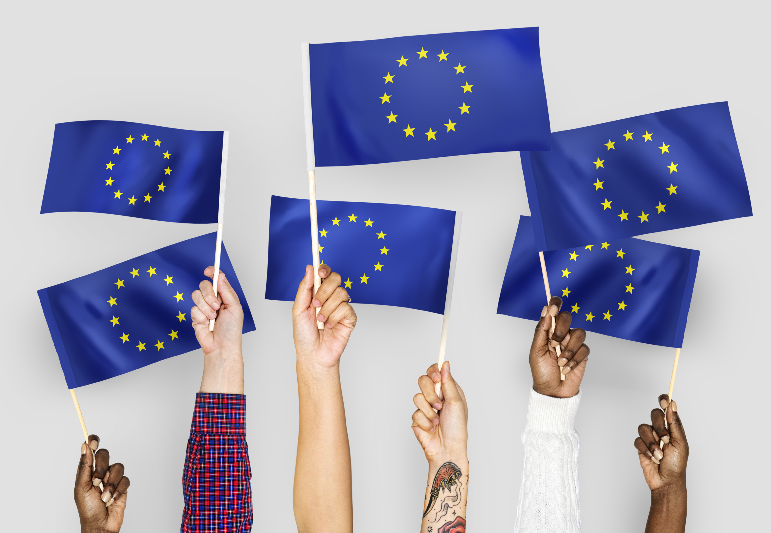 ręce machające flagami Unii Europejskiej