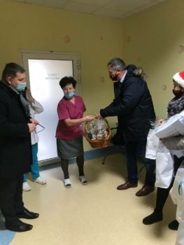 Grupa osób na szpitalnym korytarzu przekazuje podarunki