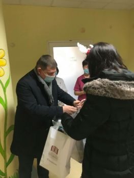 Grupa osób na szpitalnym korytarzu przekazuje podarunki