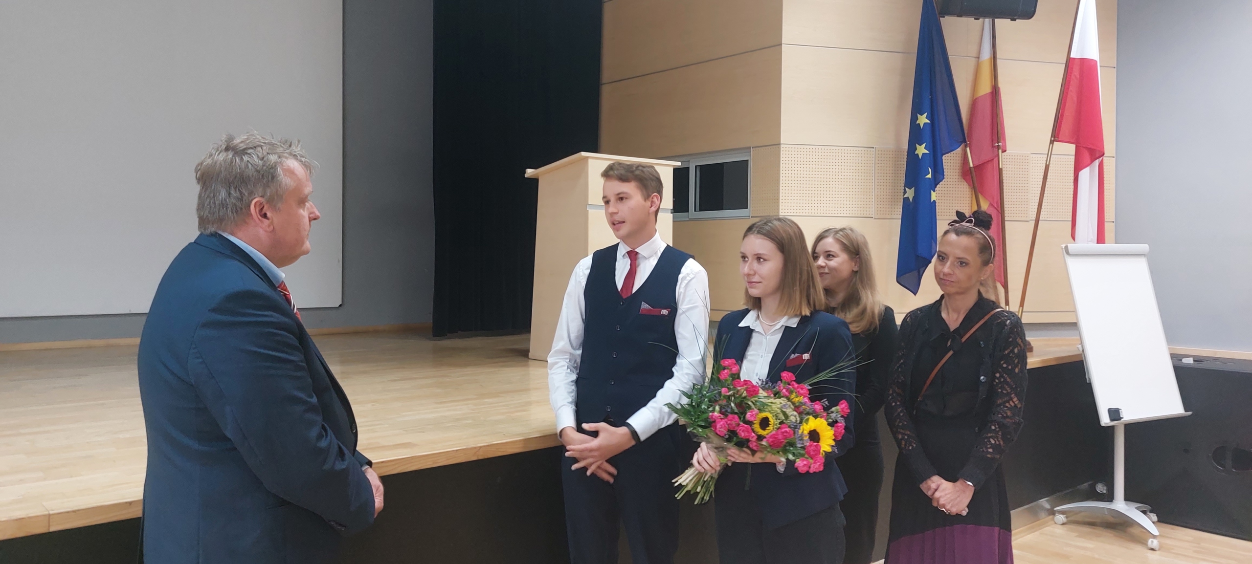 Przedstawiciele Samorządu Uczniowskiego wręczają kwiaty nowemu dyrektorowi szkoły