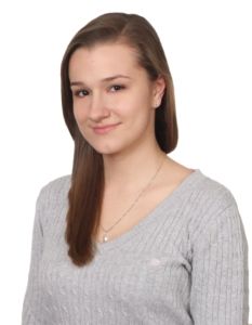 Absolwentka roku 2016, technikum. Brunetka z długimi włosami w szarym sweterku.