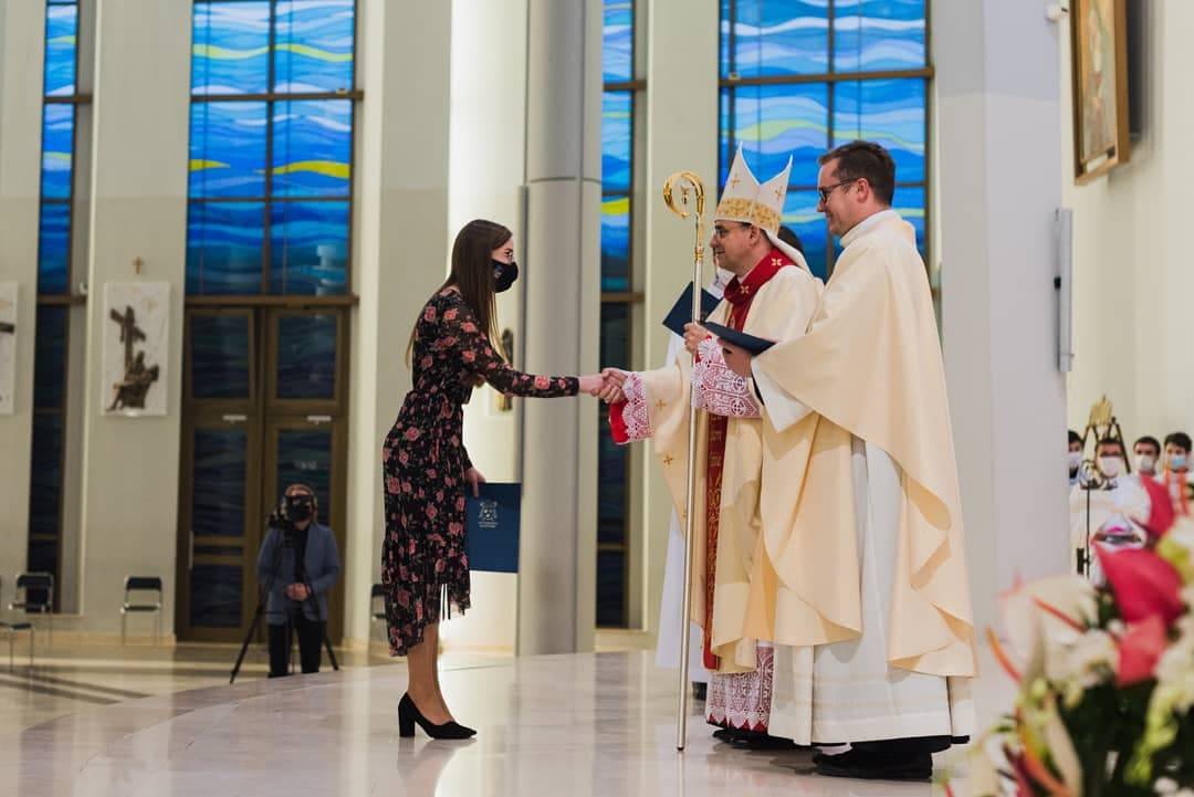 dziewczyna na ołtarzu przyjmuje wyróżniene od biskupa