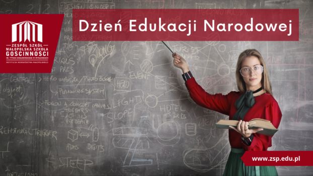 Na zdjęciu kobieta w okularach, czerwonej bluzce i zielonej spódnicy, wskazuje na szkolną tablicę z napisem dzień edukacji narodowej